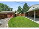 Fenced backyard with covered patio, lush green lawn, detached garage and landscaped borders at 2549 Holly St, Denver, CO 80207