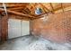 Garage interior showcasing brick walls, a white door, exposed wood, and concrete floor at 2549 Holly St, Denver, CO 80207