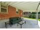 Covered brick patio with sofa and glass-topped coffee and side tables offers a shady backyard retreat at 2549 Holly St, Denver, CO 80207