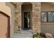 Close-up view of home's front door with stone archway, sconces, and an inviting wreath at 5149 Le Duc Ln, Castle Rock, CO 80108