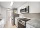 Modern kitchen with stainless-steel appliances, granite countertops, and white cabinets at 9700 E Iliff Ave # B13, Denver, CO 80231