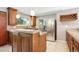 Well-lit kitchen with granite countertops, stainless steel refrigerator, a wine rack and custom wood cabinets at 6545 S Balsam Ct, Littleton, CO 80123
