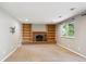 Spacious living room featuring a brick fireplace, built-in bookshelves, plush carpet and neutral paint at 6545 S Balsam Ct, Littleton, CO 80123