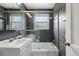 Modern bathroom with gray tiles, a glass-enclosed tub/shower combination, and a sleek vanity at 1376 Ivanhoe St, Denver, CO 80220