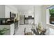Bright kitchen with stainless steel appliances, white cabinets and a dining area with modern glass table at 1376 Ivanhoe St, Denver, CO 80220