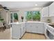 Bright kitchen features white cabinets, an island, and a large window with natural light and view of trees at 207 Short Pl, Louisville, CO 80027