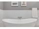 Sleek white soaking tub with modern fixtures, and a neutral gray color palette at 1588 Blackwood Ct, Erie, CO 80516