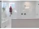 Modern bathroom with white tiled shower, glass door, bench, and bright window with plant at 1588 Blackwood Ct, Erie, CO 80516