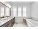 Bright bathroom features a soaking tub and double sink vanity with modern fixtures at 6485 E Cedar Ave, Denver, CO 80224