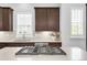 Modern kitchen with stainless steel appliances and an island with cooktop and light countertops at 6485 E Cedar Ave, Denver, CO 80224