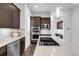 A modern kitchen with stainless steel appliances, dark wood cabinets, light countertops and flooring at 6485 E Cedar Ave, Denver, CO 80224