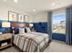 A bedroom featuring blue walls, art, a wooden headboard, plaid comforter, nightstand, and a window with striped curtains at 20802 E 66Th Ave, Aurora, CO 80019