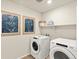 Laundry room with front load washer and dryer, wooden floors, framed art, and open shelving at 20802 E 66Th Ave, Aurora, CO 80019