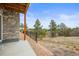 View from the patio with stone wall and fence overlooking the green space with mature trees at 650 Bishop Pine Way, Castle Rock, CO 80104
