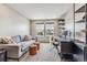 Modern living room with a comfortable gray sofa, two leather stools, stylish rug, and a sleek desk with open shelving at 6105 N Hanover St, Denver, CO 80238