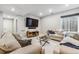 Cozy living room with two beige sofas, glass table, wall-mounted TV, and ample natural light from the basement window at 6105 N Hanover St, Denver, CO 80238