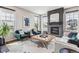 Bright living room features green armchairs, tufted ottoman, a fireplace with dark tile surround, and large windows at 6105 N Hanover St, Denver, CO 80238