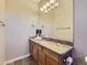 Bathroom with wooden cabinets, granite countertops, and a large mirror with decorative light fixture above the sink at 5603 Twilight Way, Parker, CO 80134