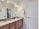Double sink bathroom vanity featuring granite countertops, wood cabinets, a bright mirror, and a glass door shower at 5603 Twilight Way, Parker, CO 80134