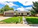 Charming ranch-style home with a well-manicured lawn, mature trees, and a two-car garage on a sunny day at 17177 E Milan Cir, Aurora, CO 80013