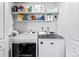 Well-organized laundry room with modern washer and dryer units and overhead shelving for storage at 17177 E Milan Cir, Aurora, CO 80013