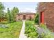 Charming brick home featuring a beautifully landscaped backyard with mature trees and a pathway at 5044 W Moncrieff Pl, Denver, CO 80212