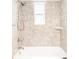 Bathtub and shower with neutral tile and a decorative accent border at 5044 W Moncrieff Pl, Denver, CO 80212