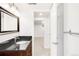 Well-lit bathroom featuring a dark countertop and a door leading to the finished basement at 5044 W Moncrieff Pl, Denver, CO 80212