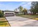 Inviting single-story home featuring a large driveway, a well-maintained lawn, and mature trees providing ample shade at 5054 W 61St Dr, Arvada, CO 80003