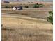 Rolling hills with dry grass and a distant house and barn with cattle grazing at 2981 Rock Cir, Elizabeth, CO 80107