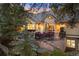 Inviting backyard patio with outdoor seating, lush landscaping, and exterior lighting at twilight at 315 Prospect Dr, Castle Rock, CO 80108