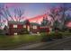 Charming red and brick home with lush green lawn and mature trees at sunset at 10978 W Ada Pl, Lakewood, CO 80226