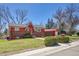 Charming red and brick home with lush green lawn and mature trees on a sunny day at 10978 W Ada Pl, Lakewood, CO 80226