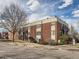 Red brick apartment building featuring balconies, green grass, mature trees, and a parking area at 5995 W Hampden Ave # 23, Denver, CO 80227