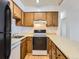 Galley-style kitchen with wood cabinets, laminate countertops, white appliances, and a wood-look vinyl floor at 5995 W Hampden Ave # 23, Denver, CO 80227