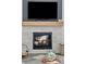 Close-up of modern fireplace with stone surround, wood mantel, and decorative logs at 1301 Sidewinder Cir, Castle Rock, CO 80108