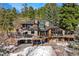 Stunning multi-level stone house with a large deck nestled in a wooded landscape, providing serene outdoor living spaces at 4398 Cameyo Rd, Indian Hills, CO 80454