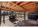 Covered outdoor bar area with seating, stone fireplace, and views of the snowy landscape at 4398 Cameyo Rd, Indian Hills, CO 80454