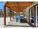 Covered patio with ping pong table, stone siding, and backyard views at 4398 Cameyo Rd, Indian Hills, CO 80454