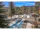 A pristine pool is surrounded by lounge chairs and a lush forest landscape with views of the mountains at 4398 Cameyo Rd, Indian Hills, CO 80454