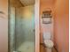 Small bathroom featuring a glass enclosed shower, a toilet, and shelving on salmon colored walls at 10852 Conifer Mountain Rd, Conifer, CO 80433