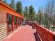 Spacious red deck features a grill, seating, and a beautiful view of the surrounding trees at 10852 Conifer Mountain Rd, Conifer, CO 80433