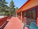 Spacious red deck with forest views, railing, seating and access to the home's interior at 10852 Conifer Mountain Rd, Conifer, CO 80433