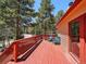Spacious red deck features seating and a beautiful view of the surrounding forest at 10852 Conifer Mountain Rd, Conifer, CO 80433