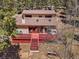 Aerial view of the exterior of the home with a large deck surrounded by dense trees at 10852 Conifer Mountain Rd, Conifer, CO 80433