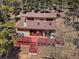 Aerial view of a two-story home with a red deck surrounded by a lush forest at 10852 Conifer Mountain Rd, Conifer, CO 80433