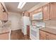 Functional kitchen with light wood cabinetry, tile backsplash, and white appliances at 1828 Stratford Ln, Longmont, CO 80503
