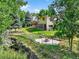 Fenced backyard with lawn, mature trees, stone patio, and a view of the creek running behind the property at 8165 W Stene Dr, Littleton, CO 80128