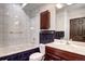 Well-lit bathroom featuring a marble-top vanity, tiled tub/shower, and dark wood accents at 925 N Emerson St, Denver, CO 80218