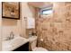 This well-lit bathroom features travertine tile, a vanity and large mirror for a sleek modern feel at 2838 Forest St, Denver, CO 80207
